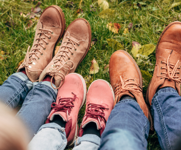 Image of three pairs of feet in pink shoes, and sandy coloured boots wearing denim jeans taken from above. Eco sneakers and other fair trade shoes don't have to break the bank!