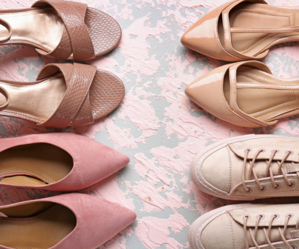 Image of a pair of pink ballet flats, two coffee coloured high heels, and khaki coloured sneakers pointed at each other two by two taken from above on a floral background. Sustainable shoes for women, men, and kids do exist!