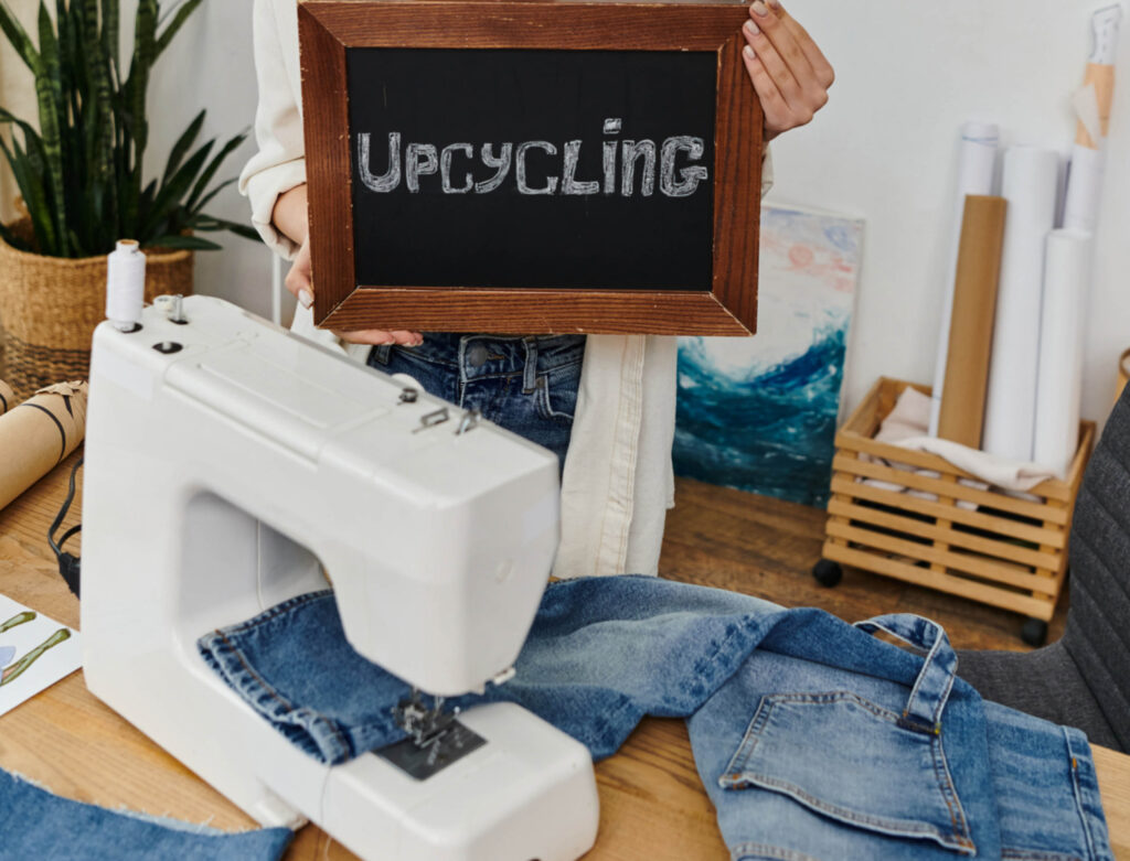 Image of a sewing machine and pair of jeans with an chalkboard sign that says "upcycling"