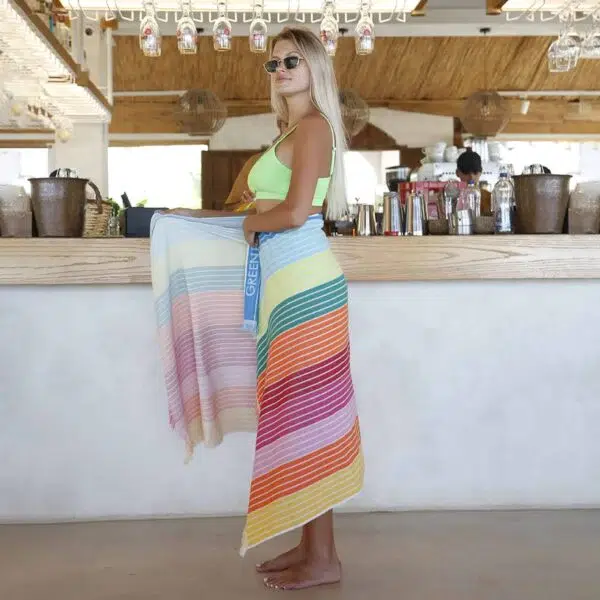 Image of a woman wearing a colourful towel at a beach bar.