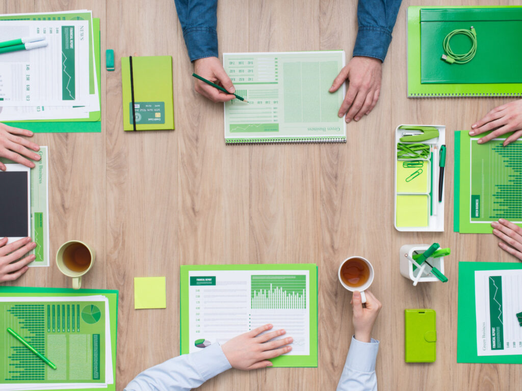 Image of two people working at a desk filled with eco-conscious office supplies taken from above.