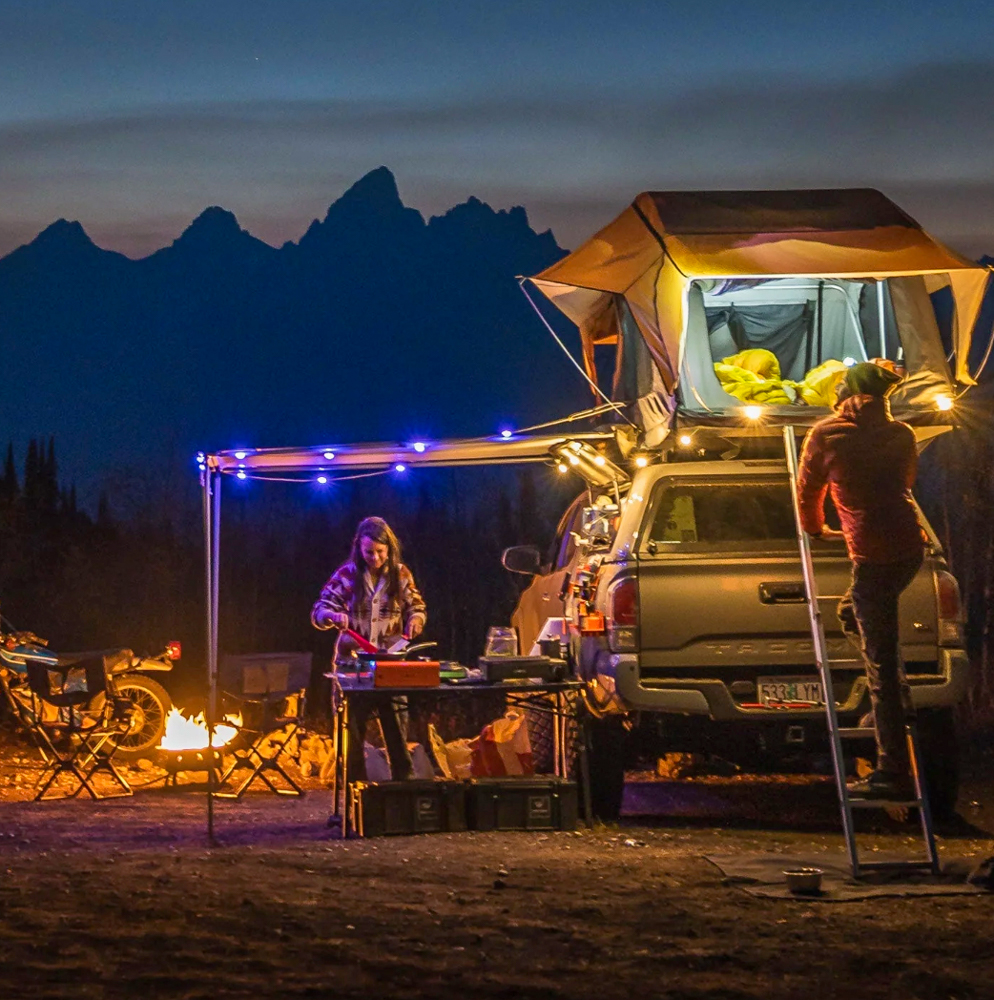 Image of an elaborate camp set up with solar lights and an evening mountainous backdrop.