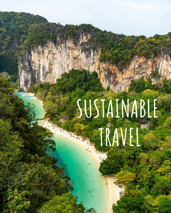 Image of a turquoise beach surrounded by lush green jungle and a towering cliff taken from above with the title "Sustainable Travel" overlaid.
