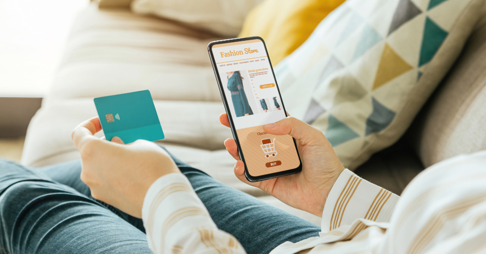 Image of a pair of hands holding a smartphone and a credit card while they online shop.