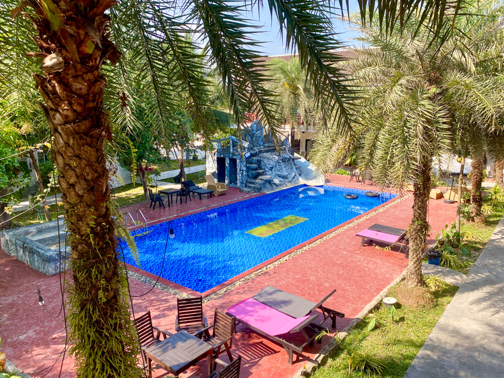 Image of the pool surrounded by palm trees at Savanh Sunset View Resort, a budget-friendly accommodation in Vang Vieng Laos.