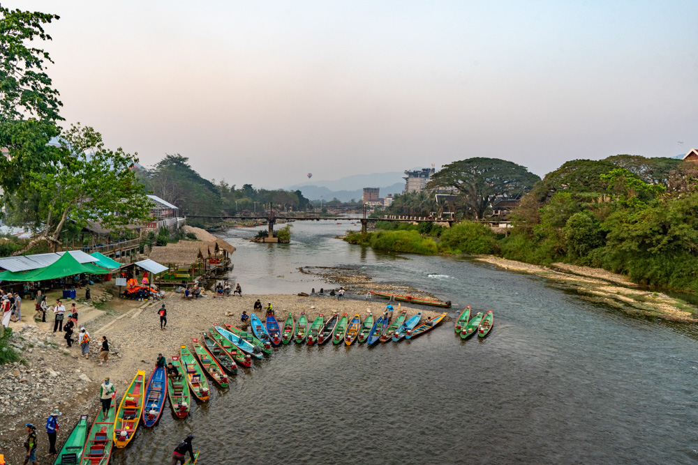 Image of many boats on the bank of the Nam Song River in Vang Vieng taken from above. Our Laos travel guide can help you travel sustainably.