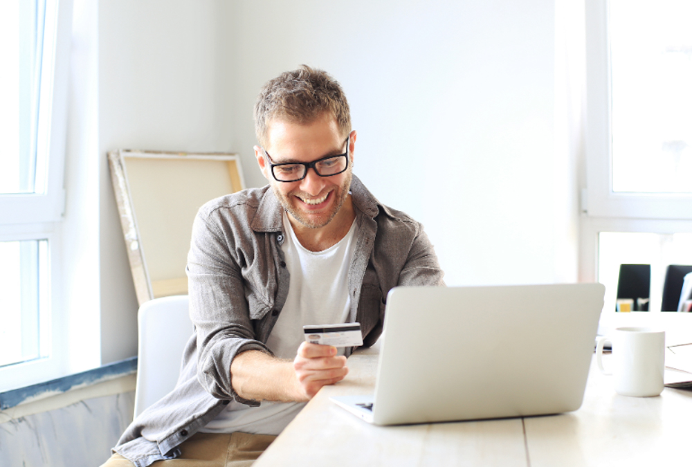 Image of a man using an online secondhand shopping platform on his laptop at home. 